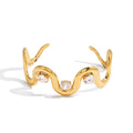 Gold bracelet with wavy design and clear gemstones on a white background