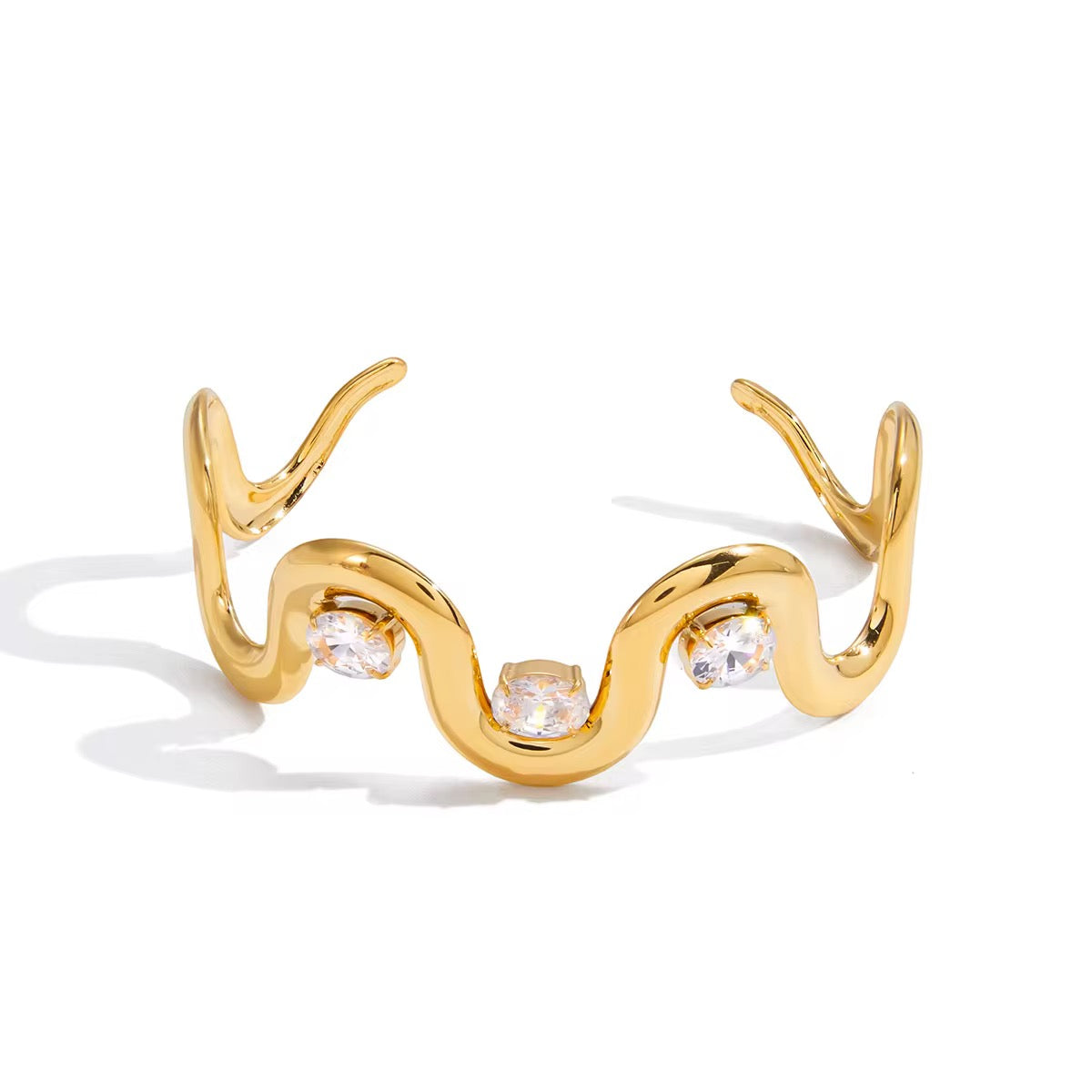 Gold bracelet with wavy design and clear gemstones on a white background